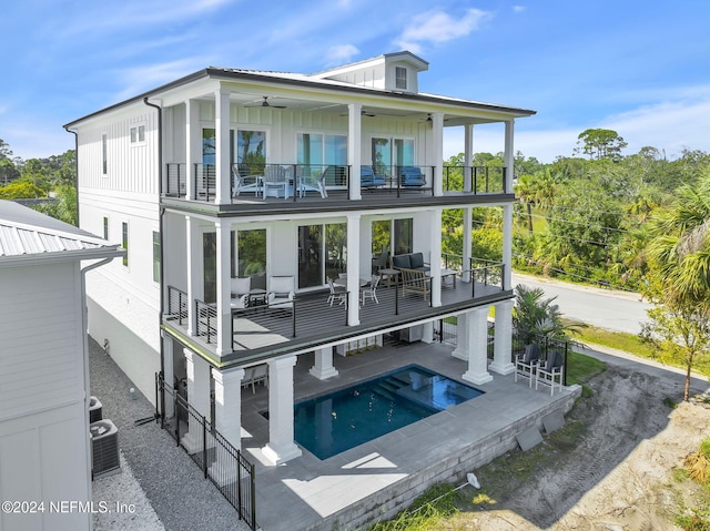 rear view of house with a patio, board and batten siding, an outdoor pool, a balcony, and ceiling fan