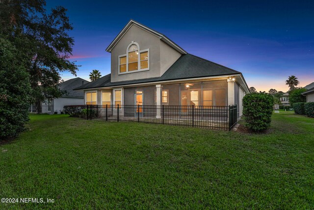 back house at dusk with a lawn