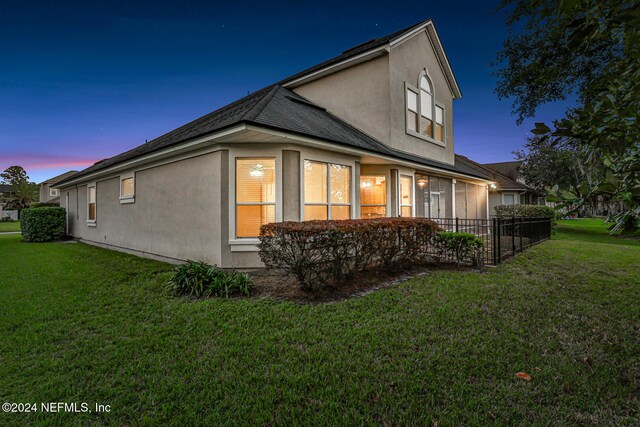 property exterior at dusk featuring a lawn