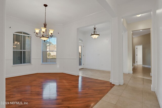 empty room featuring light hardwood / wood-style floors, crown molding, and a chandelier