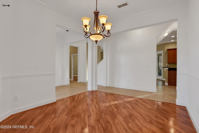 empty room with light hardwood / wood-style flooring and an inviting chandelier