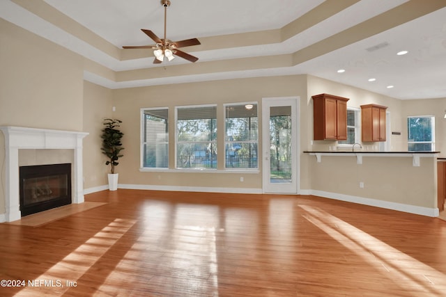 2176 Autumn Cove Cir, Fleming Island, FL 32003 - unfurnished living room featuring light wood finished floors, a ceiling fan, a tray ceiling, a fireplace, and recessed lighting