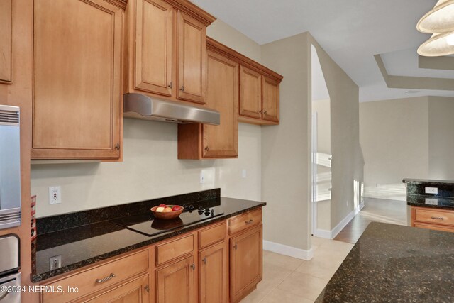 kitchen with dark stone countertops, black electric cooktop, hanging light fixtures, and light tile patterned floors