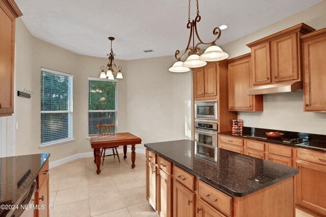 kitchen with stainless steel appliances, pendant lighting, dark stone countertops, a center island, and light tile patterned flooring