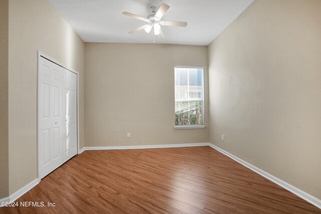 unfurnished bedroom featuring hardwood / wood-style floors, a closet, and ceiling fan