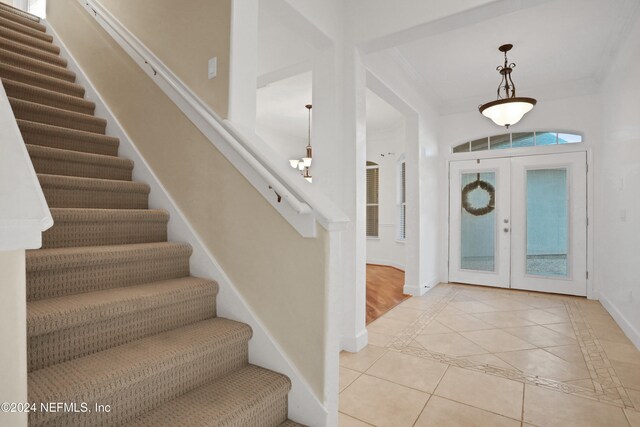 entryway featuring french doors, light tile patterned flooring, and ornamental molding