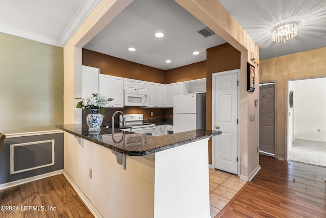 kitchen with light hardwood / wood-style floors, white appliances, kitchen peninsula, and white cabinetry