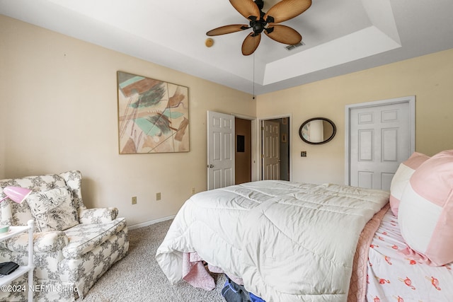 carpeted bedroom featuring a tray ceiling and ceiling fan