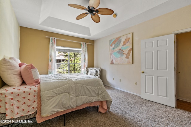 bedroom featuring ceiling fan, a raised ceiling, and carpet floors