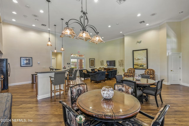 dining room with sink, crown molding, dark wood-type flooring, and an inviting chandelier