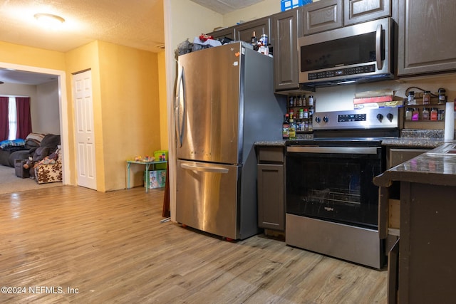 kitchen featuring appliances with stainless steel finishes, a textured ceiling, light hardwood / wood-style floors, and dark brown cabinets