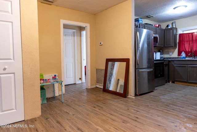 kitchen featuring a textured ceiling, light hardwood / wood-style floors, sink, and stainless steel appliances