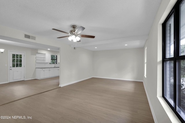 unfurnished living room with ceiling fan, wood-type flooring, and a textured ceiling