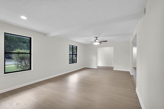 empty room with ceiling fan, a textured ceiling, and hardwood / wood-style flooring