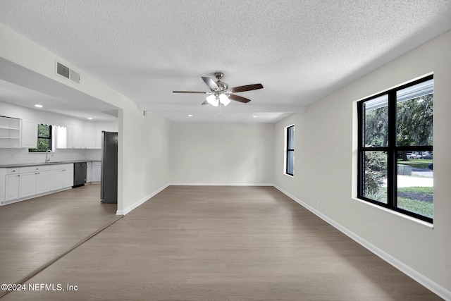 empty room with ceiling fan, sink, a textured ceiling, and light hardwood / wood-style flooring