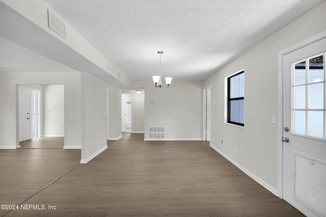 interior space with dark hardwood / wood-style flooring, a textured ceiling, and an inviting chandelier