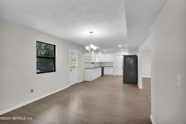 unfurnished living room with wood-type flooring, a textured ceiling, and an inviting chandelier