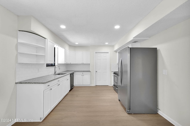 kitchen featuring white cabinets, sink, decorative backsplash, light hardwood / wood-style floors, and stainless steel appliances