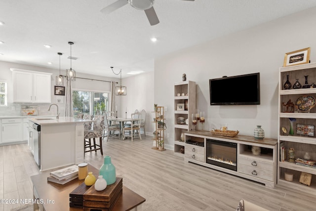 living room with ceiling fan, light wood-type flooring, and sink