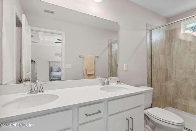 bathroom with a tile shower, vanity, and toilet