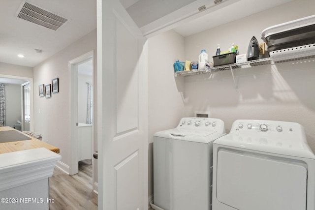 washroom with washing machine and dryer and light hardwood / wood-style floors