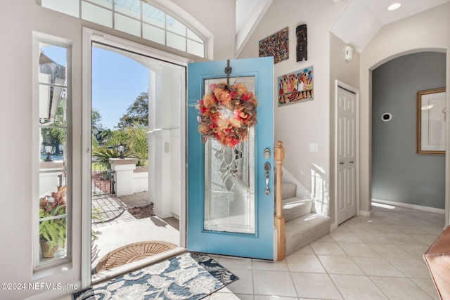 doorway with light tile patterned flooring and lofted ceiling