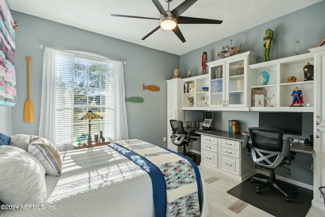 bedroom featuring ceiling fan, built in desk, and light wood-type flooring