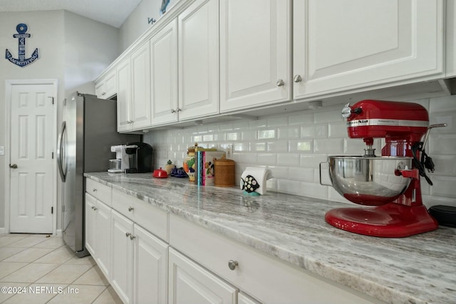 kitchen with tasteful backsplash, light stone counters, white cabinets, and light tile patterned floors