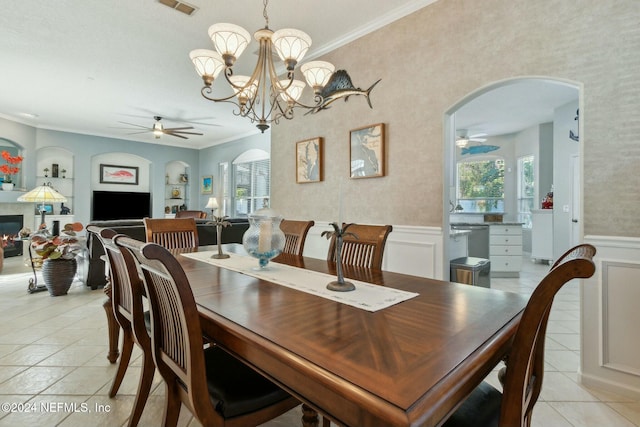 tiled dining space with ceiling fan with notable chandelier and crown molding