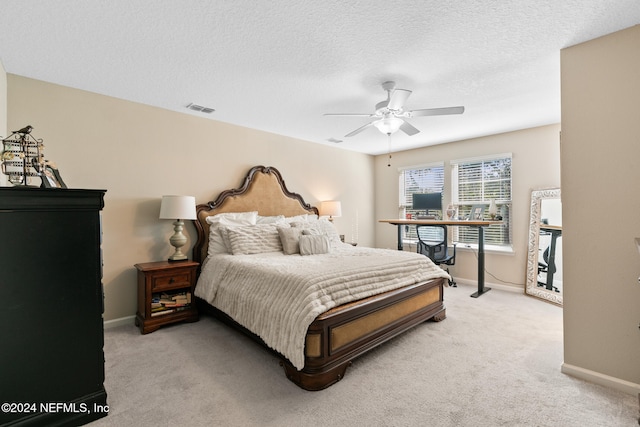 carpeted bedroom featuring ceiling fan and a textured ceiling