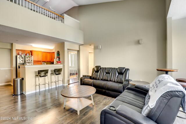 living room featuring high vaulted ceiling and wood-type flooring