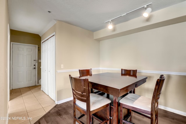 dining space with light hardwood / wood-style flooring, rail lighting, and a textured ceiling