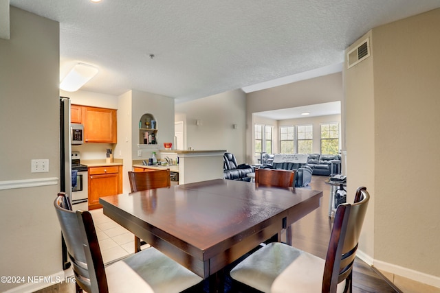 dining area featuring light tile patterned floors and a textured ceiling