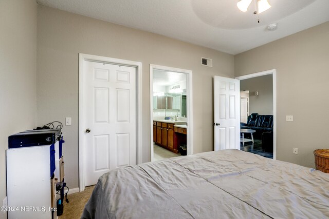 bedroom with light carpet, a closet, ensuite bath, and ceiling fan