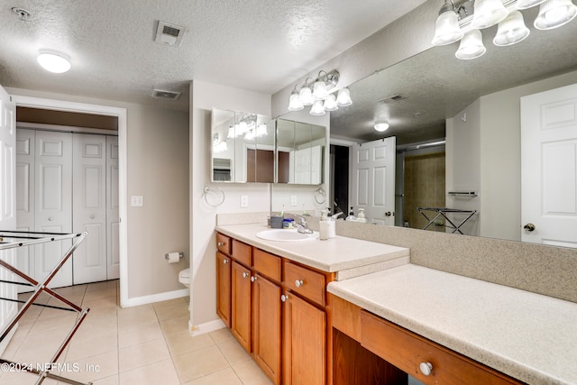 bathroom with tile patterned flooring, a textured ceiling, toilet, vanity, and a shower with shower door