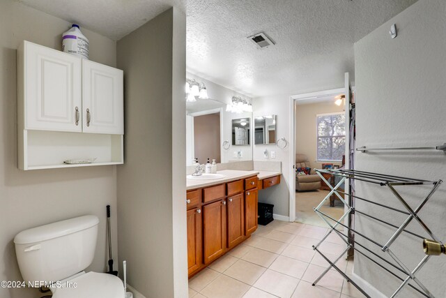 bathroom featuring tile patterned flooring, vanity, a textured ceiling, and toilet