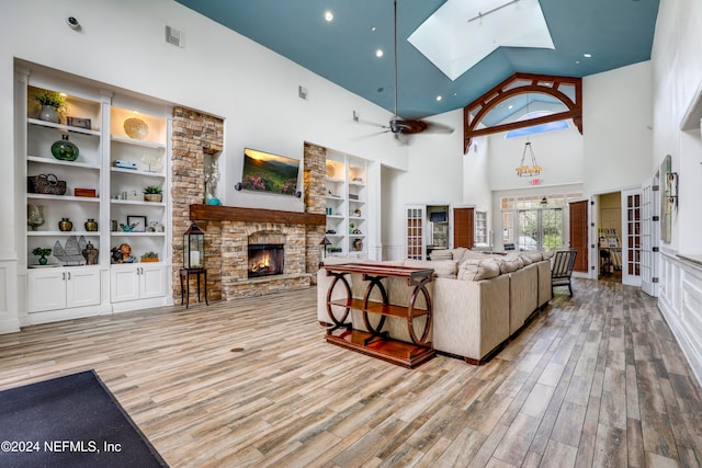 living room with a skylight, ceiling fan, high vaulted ceiling, and light hardwood / wood-style floors