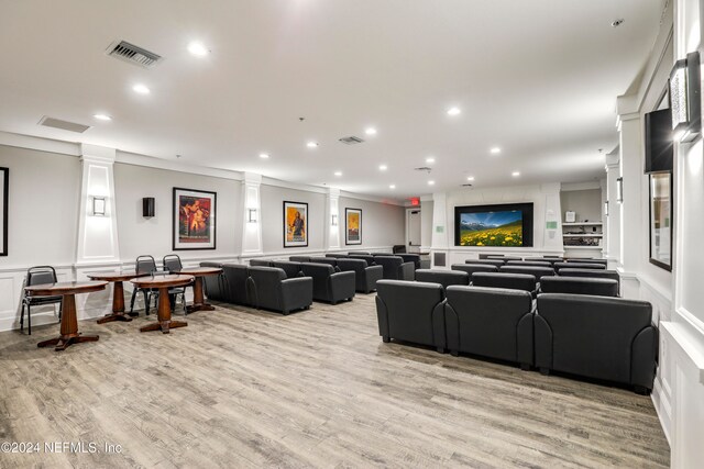 interior space with light hardwood / wood-style floors, crown molding, and decorative columns