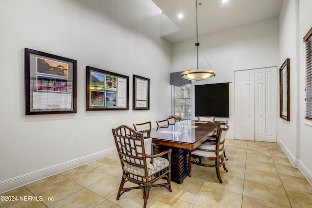 dining area featuring light tile patterned floors and a towering ceiling