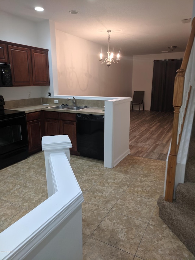 kitchen featuring sink, an inviting chandelier, pendant lighting, light hardwood / wood-style floors, and black appliances