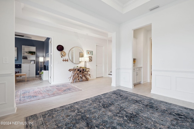 hallway featuring light wood-type flooring, built in features, and ornamental molding