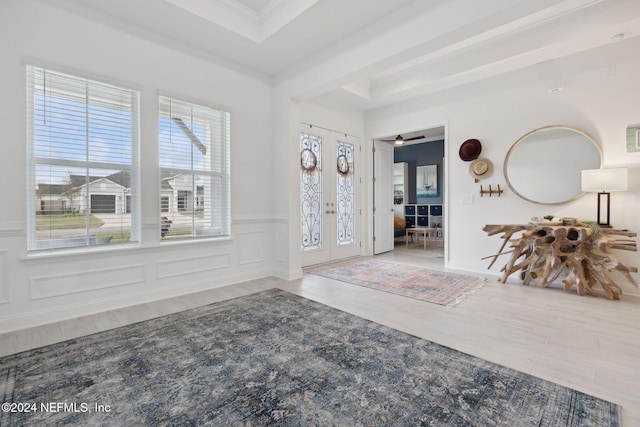 entrance foyer featuring french doors, a raised ceiling, ceiling fan, light wood-type flooring, and ornamental molding