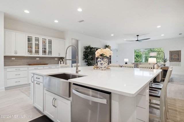 kitchen with dishwasher, a center island with sink, a kitchen breakfast bar, light hardwood / wood-style floors, and white cabinetry