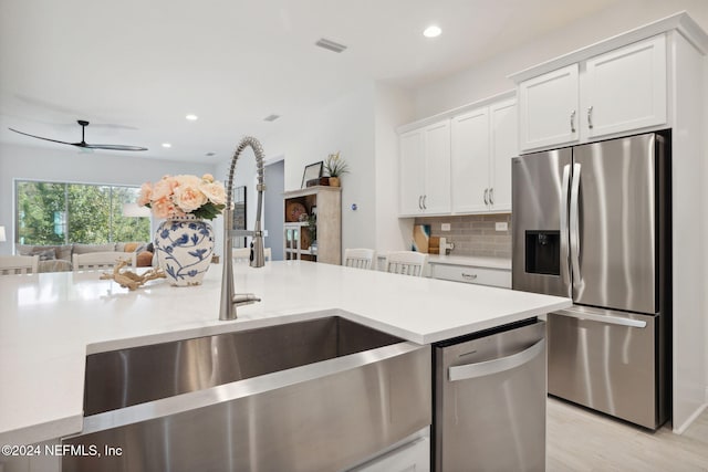 kitchen with white cabinetry, sink, stainless steel appliances, tasteful backsplash, and light hardwood / wood-style floors