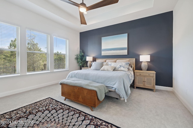 bedroom featuring a tray ceiling, ceiling fan, and light carpet