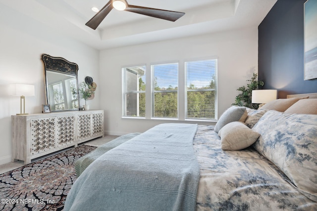 carpeted bedroom featuring a tray ceiling and ceiling fan