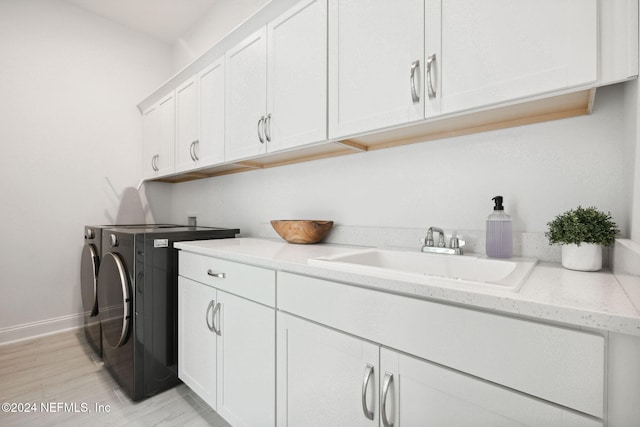 washroom with washer and clothes dryer, sink, cabinets, and light hardwood / wood-style floors