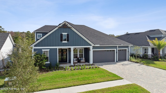 view of front of home with a garage, a porch, and a front yard