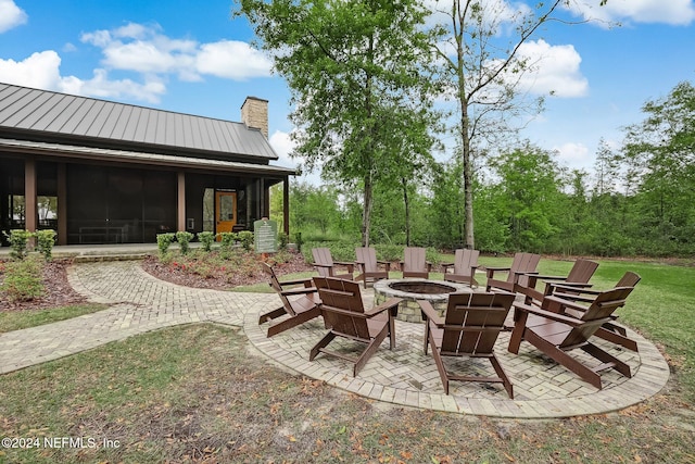 view of patio featuring a sunroom and an outdoor fire pit