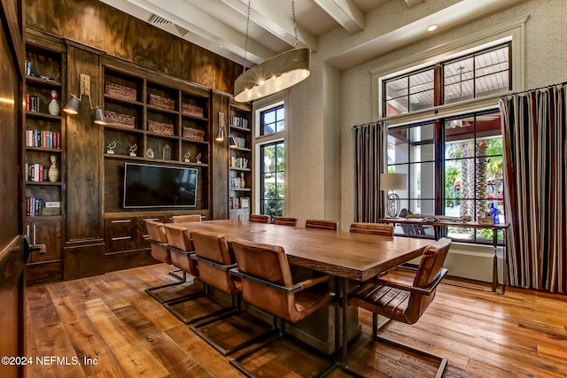 dining area with beamed ceiling, wood-type flooring, plenty of natural light, and built in shelves